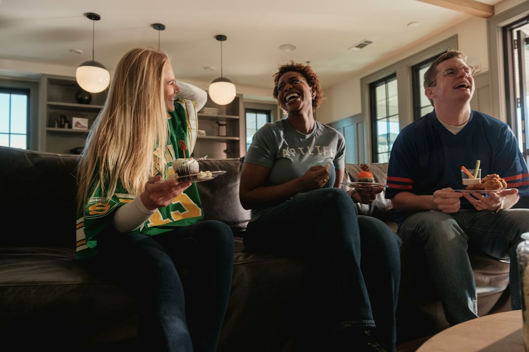 Friends laughing together while watching a football game at home